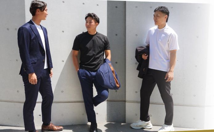 コンクリート壁の前に立つ3人
